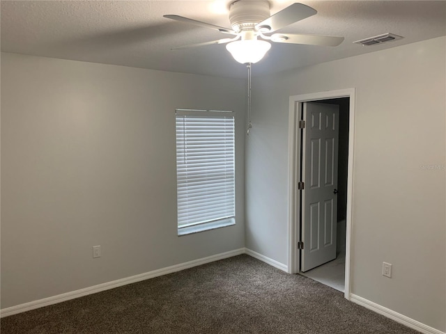 carpeted empty room with ceiling fan, a textured ceiling, visible vents, and baseboards