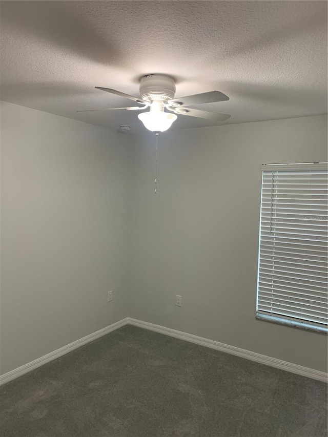 spare room with ceiling fan, dark colored carpet, a textured ceiling, and baseboards