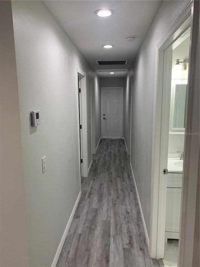 corridor with visible vents, baseboards, and wood finished floors