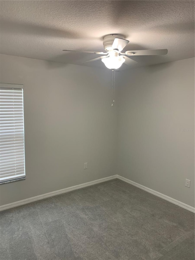 carpeted empty room with a ceiling fan, baseboards, and a textured ceiling