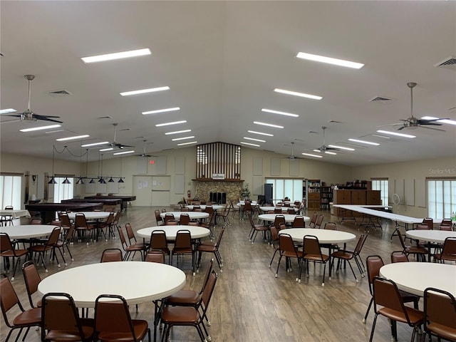 dining area featuring a ceiling fan, lofted ceiling, visible vents, and wood finished floors