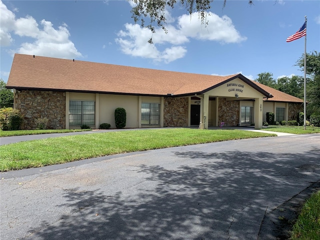 view of front of property featuring stone siding, a front lawn, and stucco siding