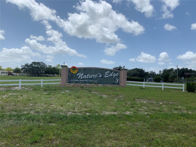 community / neighborhood sign featuring a yard, a rural view, and fence