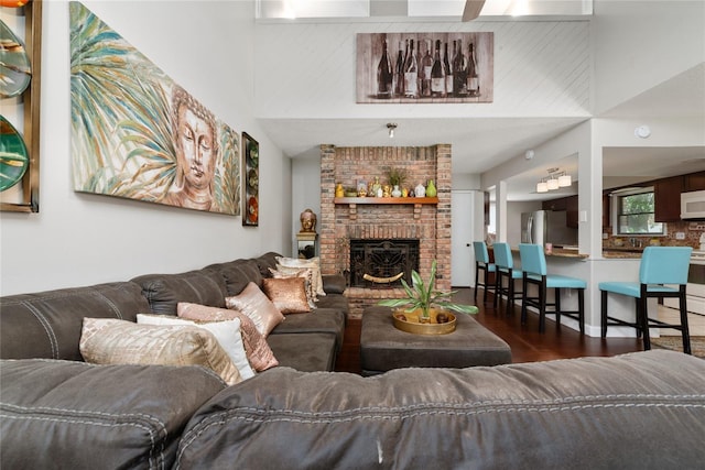 living room with brick wall, dark hardwood / wood-style flooring, and a brick fireplace