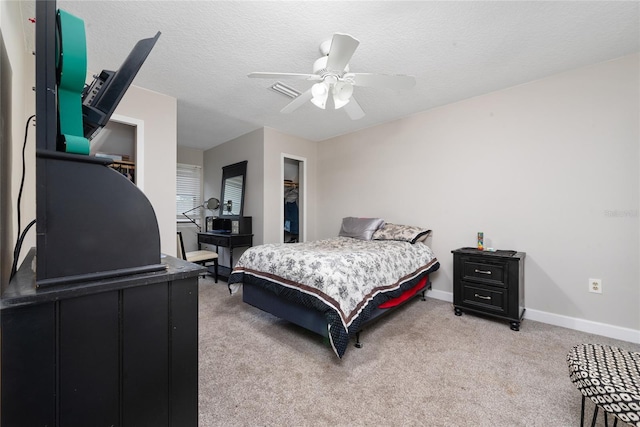 bedroom featuring ceiling fan, a closet, light carpet, and a textured ceiling