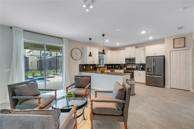 kitchen with tasteful backsplash, hanging light fixtures, kitchen peninsula, stainless steel appliances, and white cabinets