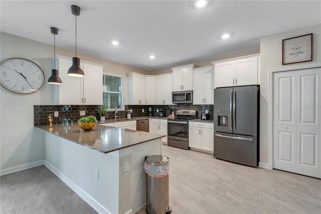 kitchen featuring appliances with stainless steel finishes, white cabinetry, hanging light fixtures, decorative backsplash, and kitchen peninsula