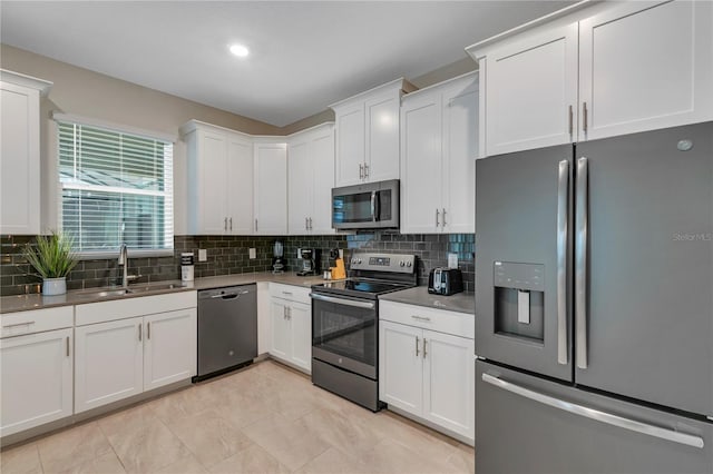 kitchen with sink, backsplash, white cabinets, and appliances with stainless steel finishes