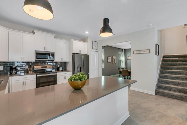 kitchen with stainless steel appliances, tasteful backsplash, hanging light fixtures, and white cabinets