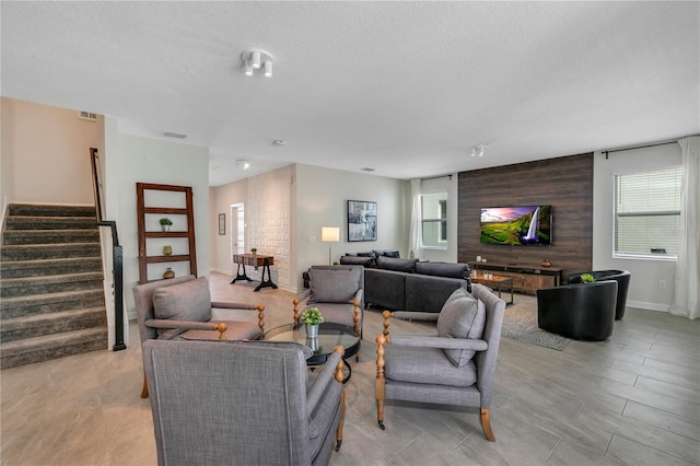 living room featuring plenty of natural light, a textured ceiling, and wood walls