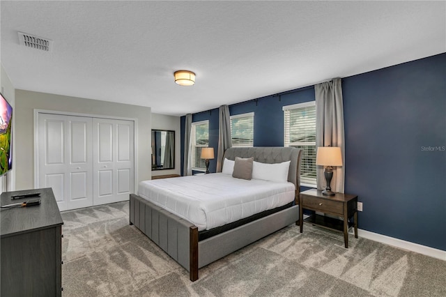 carpeted bedroom featuring a closet and a textured ceiling