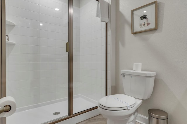 bathroom with a shower with door and toilet