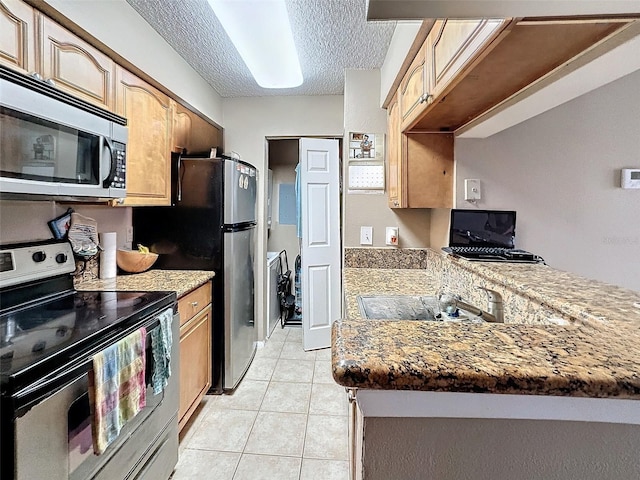 kitchen featuring light tile patterned flooring, stainless steel appliances, light stone countertops, and a textured ceiling