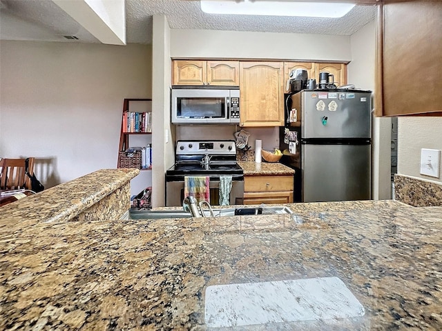 kitchen with light stone counters, light brown cabinets, a textured ceiling, and appliances with stainless steel finishes