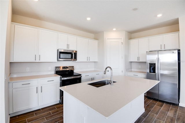 kitchen with stainless steel appliances, a kitchen island with sink, sink, and white cabinets