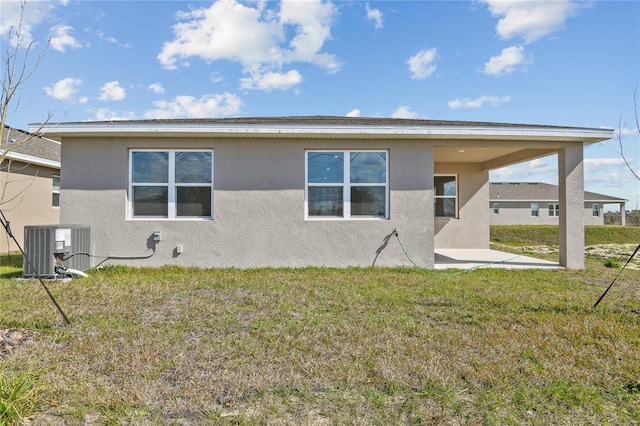 rear view of property with central AC and a lawn