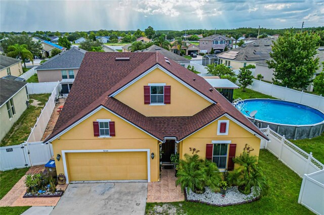 view of front of home with a garage and a fenced in pool