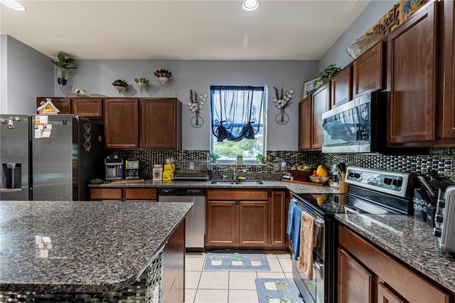 kitchen with appliances with stainless steel finishes, light tile patterned floors, backsplash, and dark stone counters