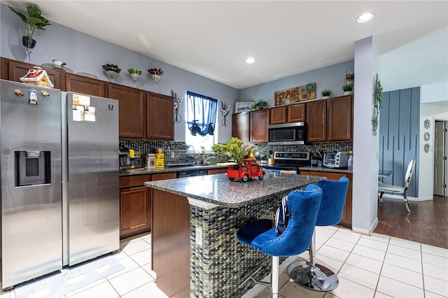 kitchen featuring a kitchen island, light wood-type flooring, tasteful backsplash, and stainless steel appliances