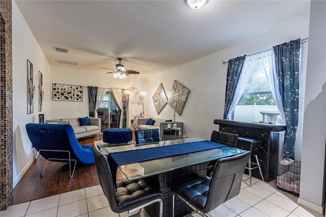 tiled dining room featuring a textured ceiling and ceiling fan