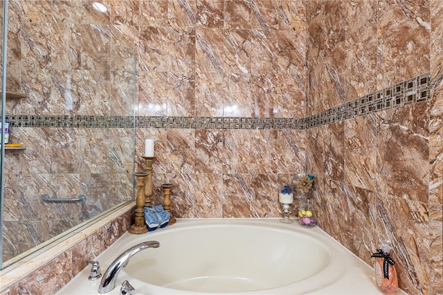 bathroom featuring a washtub and tile walls