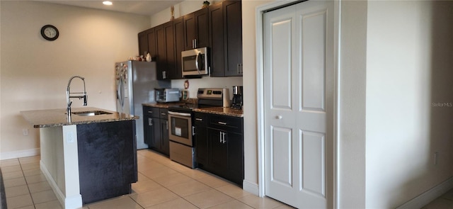 kitchen featuring light tile patterned flooring, appliances with stainless steel finishes, sink, and an island with sink