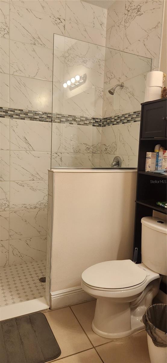 bathroom with tiled shower, tile patterned floors, and toilet