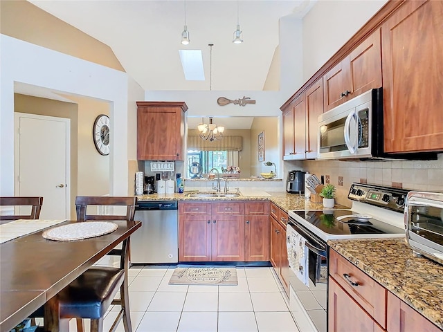 kitchen with stainless steel appliances, sink, pendant lighting, and light stone counters