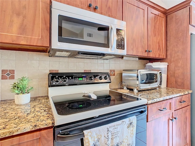 kitchen featuring backsplash, light stone countertops, and electric range