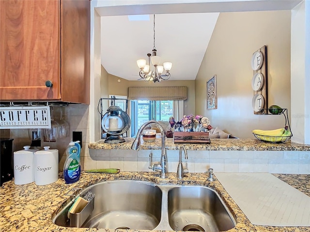 kitchen with sink, an inviting chandelier, tasteful backsplash, light stone counters, and vaulted ceiling