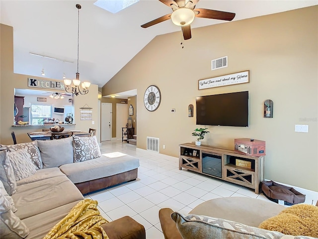 tiled living room featuring high vaulted ceiling and ceiling fan with notable chandelier