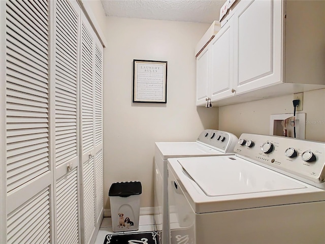 clothes washing area featuring cabinets, separate washer and dryer, and a textured ceiling