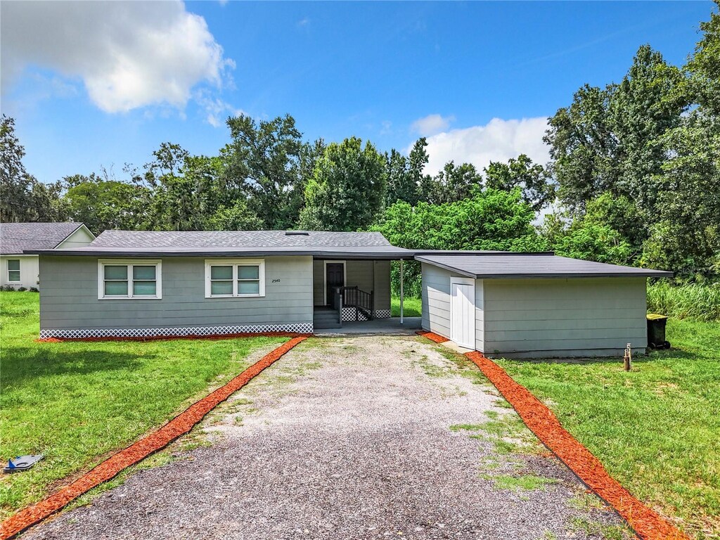 single story home featuring a garage, an outdoor structure, and a front lawn