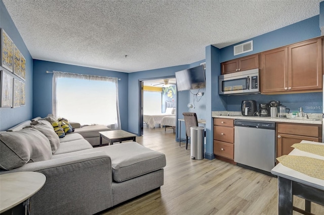 kitchen featuring appliances with stainless steel finishes, sink, light hardwood / wood-style floors, and a textured ceiling