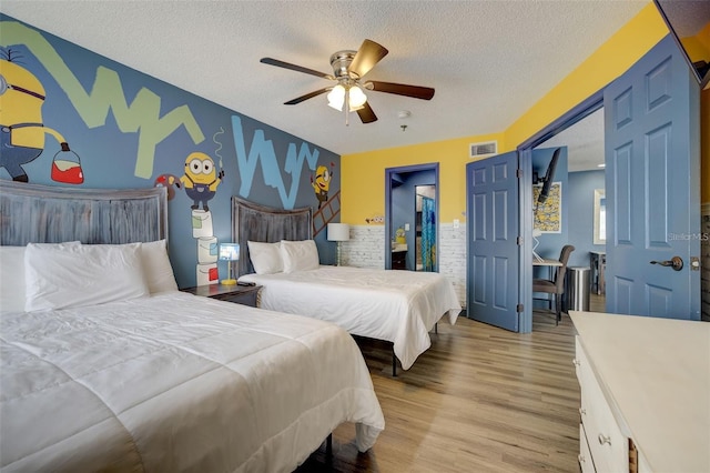 bedroom with ceiling fan, light hardwood / wood-style flooring, and a textured ceiling