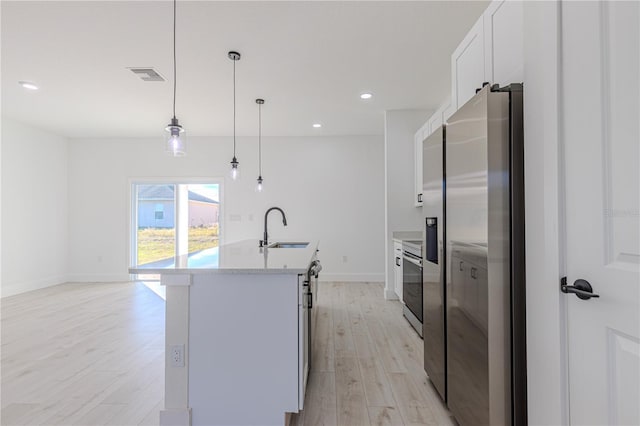 kitchen featuring stainless steel appliances, sink, decorative light fixtures, light hardwood / wood-style flooring, and white cabinetry