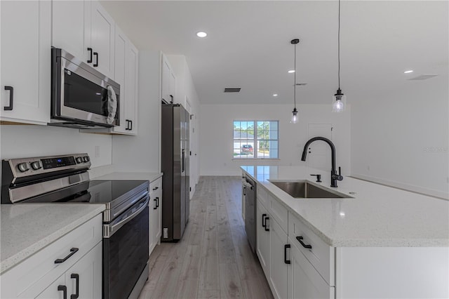 kitchen featuring sink, hanging light fixtures, light hardwood / wood-style flooring, appliances with stainless steel finishes, and white cabinetry