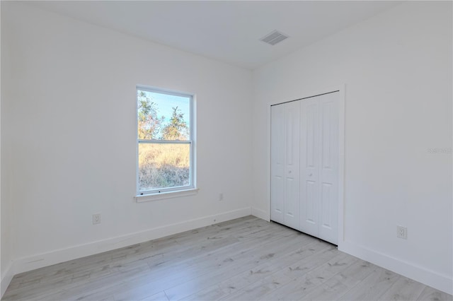 unfurnished bedroom with light wood-type flooring and a closet