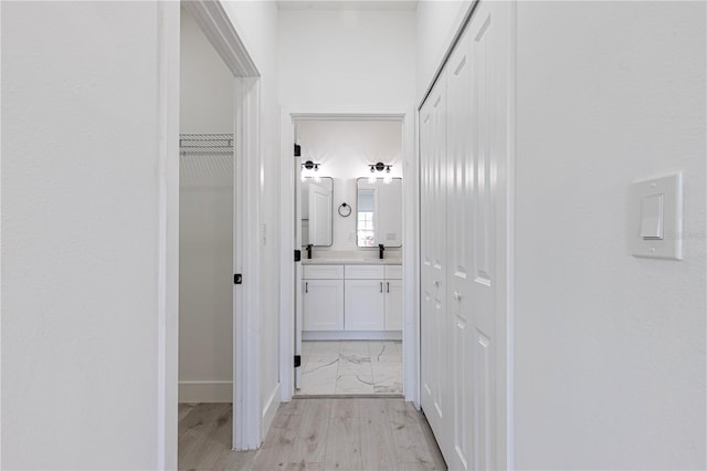 corridor with light hardwood / wood-style flooring and sink