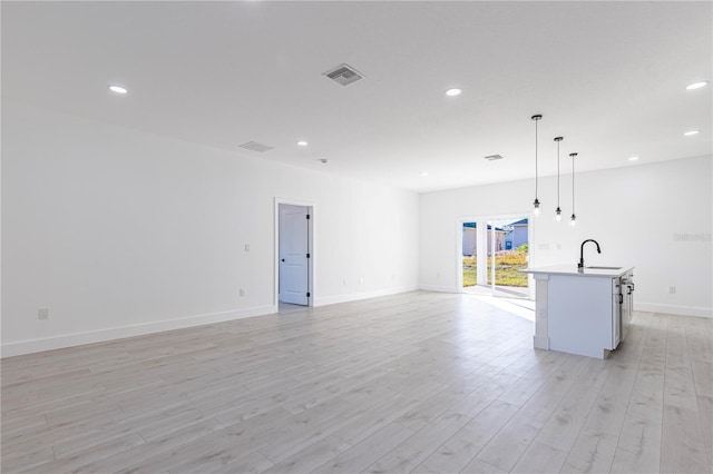 unfurnished living room featuring light hardwood / wood-style floors and sink