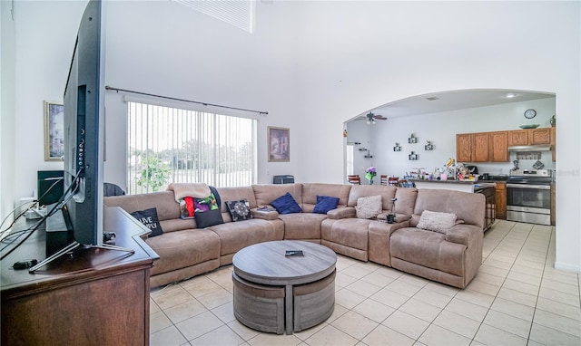 living room with a high ceiling, ceiling fan, and light tile patterned floors