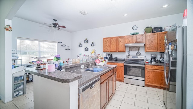 kitchen featuring appliances with stainless steel finishes, sink, light tile patterned floors, ceiling fan, and a center island with sink