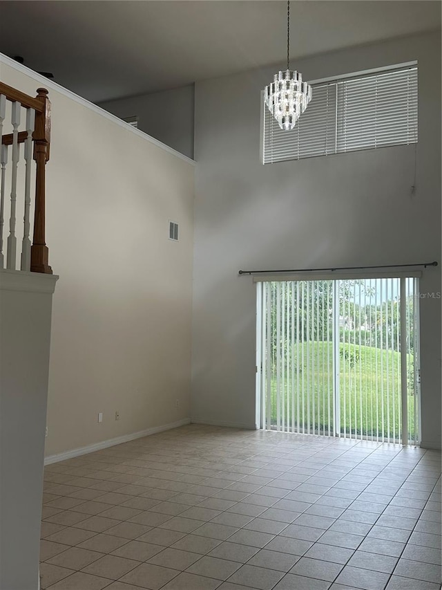 tiled empty room with an inviting chandelier and a high ceiling