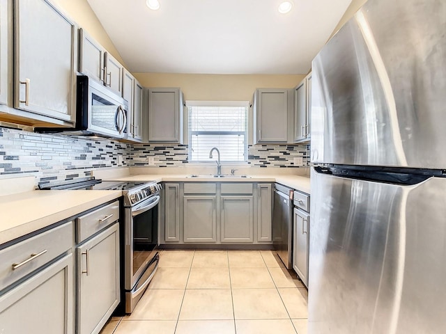 kitchen featuring sink, gray cabinetry, stainless steel appliances, tasteful backsplash, and light tile patterned flooring