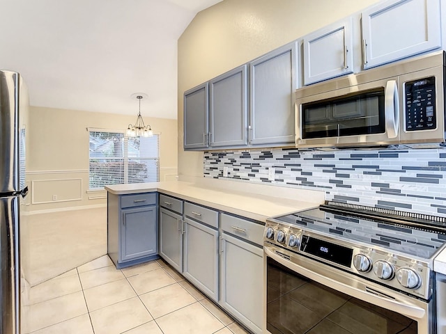 kitchen featuring gray cabinetry, decorative backsplash, hanging light fixtures, kitchen peninsula, and stainless steel appliances