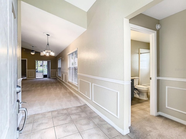 corridor featuring vaulted ceiling, light colored carpet, and a chandelier