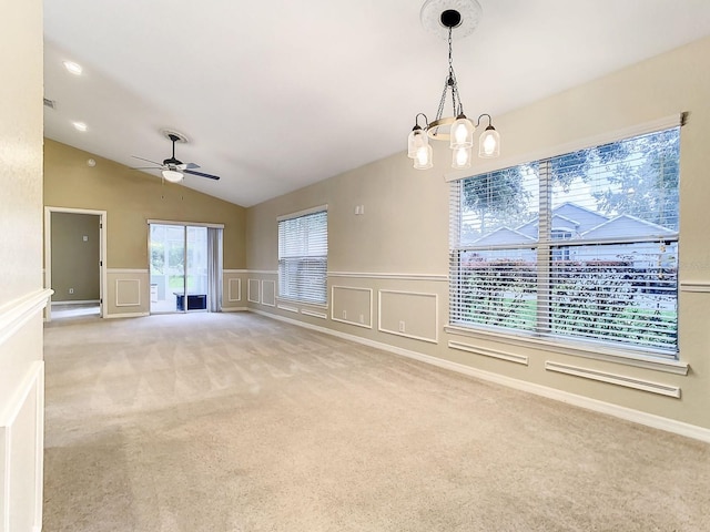 carpeted spare room with ceiling fan with notable chandelier and vaulted ceiling