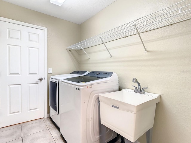 washroom featuring washing machine and dryer, sink, and light tile patterned flooring