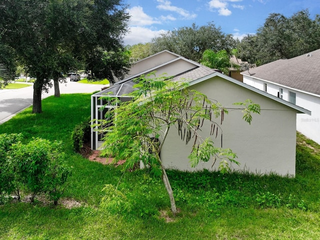 view of side of home with a yard and glass enclosure