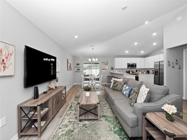 living room featuring a notable chandelier, light hardwood / wood-style flooring, and vaulted ceiling